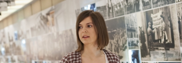 Eine junge Frau führt durch eine Ausstellung in einer Gedenkstätte. 