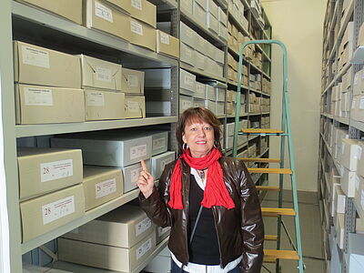 Die Freiwillige steht zwischen den hohen Regalen des Archivs.