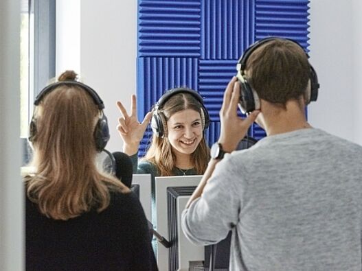 Drei Freiwillige* stehen in einem Aufnahmestudio eines Radiosenders.