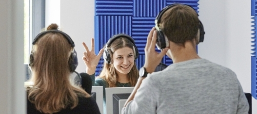 Drei Freiwillige* stehen in einem Aufnahmestudio eines Radiosenders.