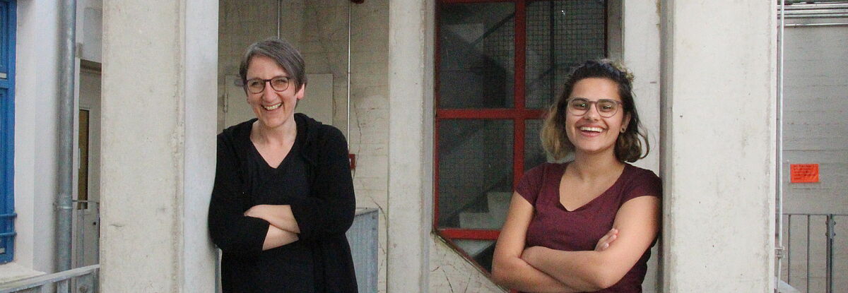 Paulina Güllü und Susanne Tod stehend lachend auf einer Terrasse.